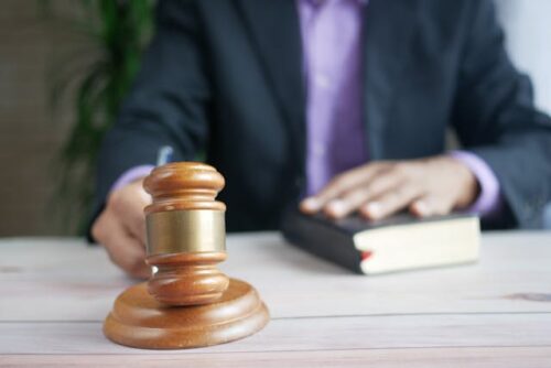 judge holding gavel with hand on book